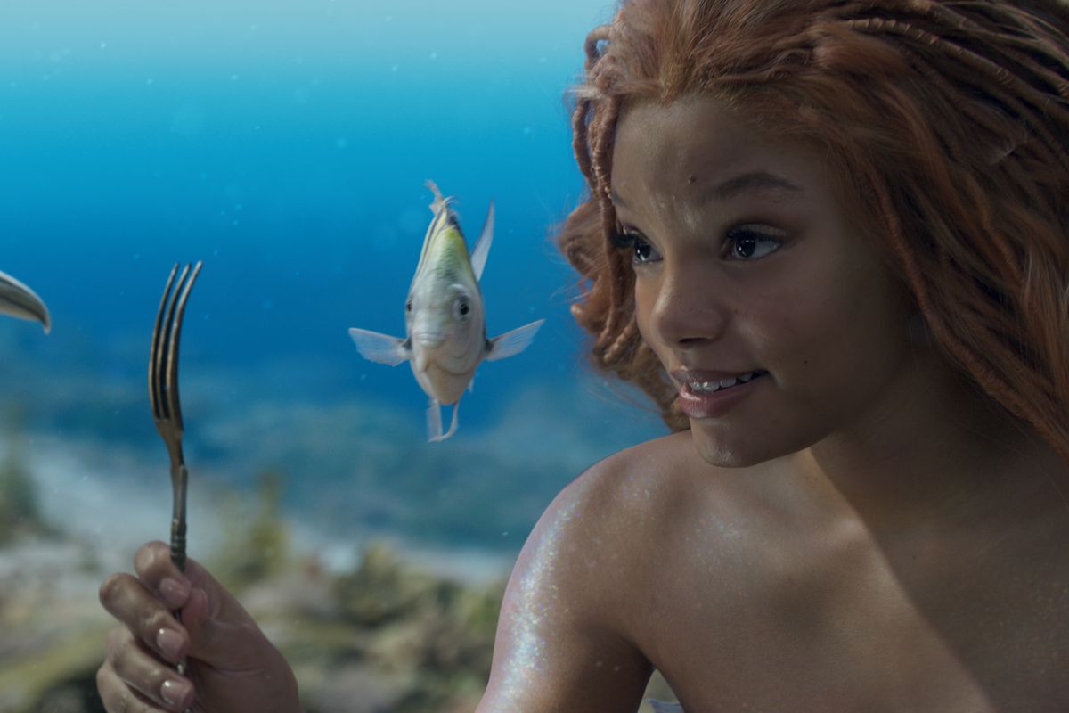 Ariel, as played by Halle Bailey, holding up a fork to show to Scuttle and Flounder