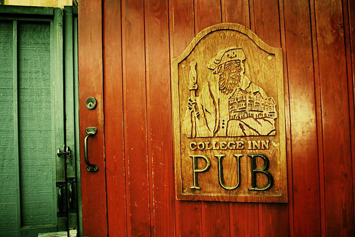 A wood door with a golden embossed sign that says the College Inn Pub with an engraved visage of a scholar and a green door to the left.