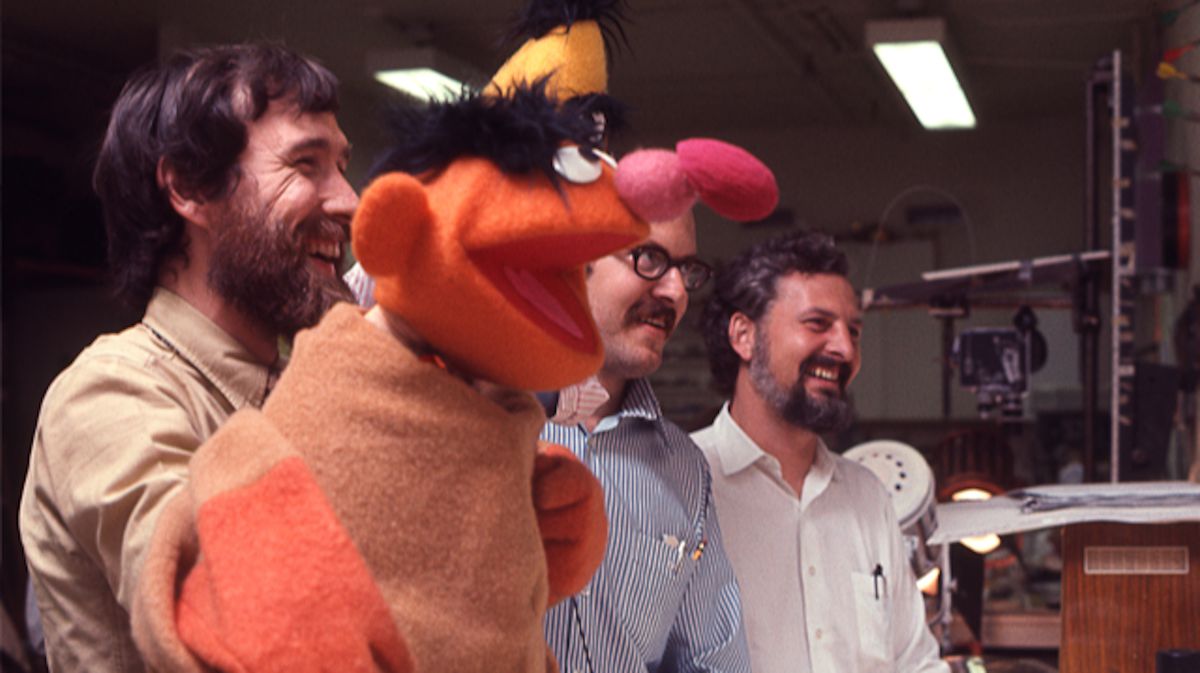 Puppeteers Jim Henson and Frank Oz and Sesame Street Jon Stone hold up an Ernie puppet in the behind-the-scenes documentary Street Gang