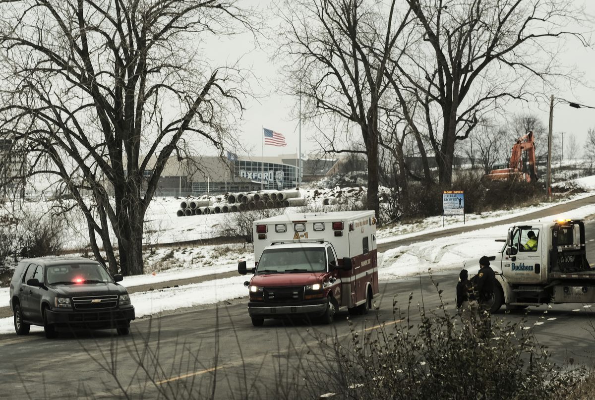 First responders set up a cordon following a shooting at a Michigan high school. There are a few inches of snow on the ground and the trees are bare.