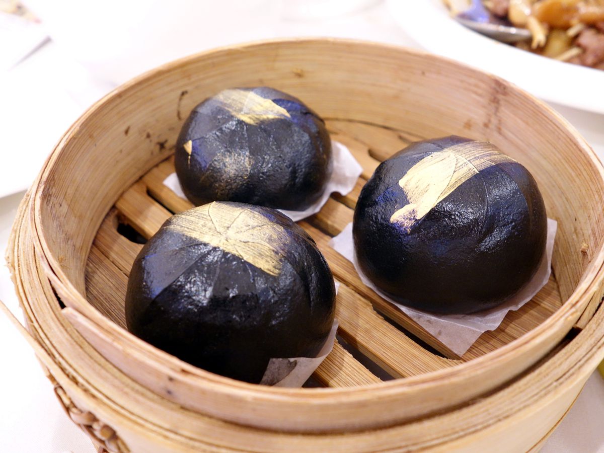 Three jet-black buns in a bamboo basket.