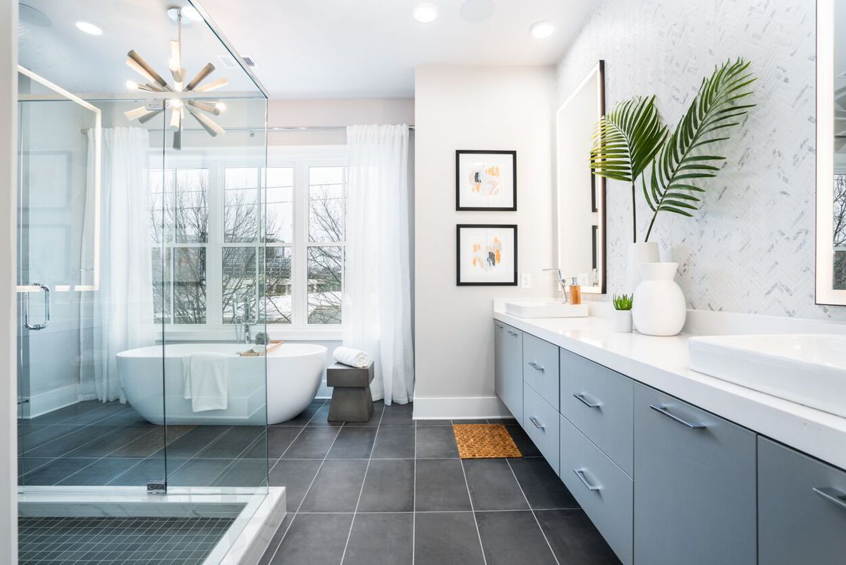 A white and gray master bathroom with a glass shower at left. 