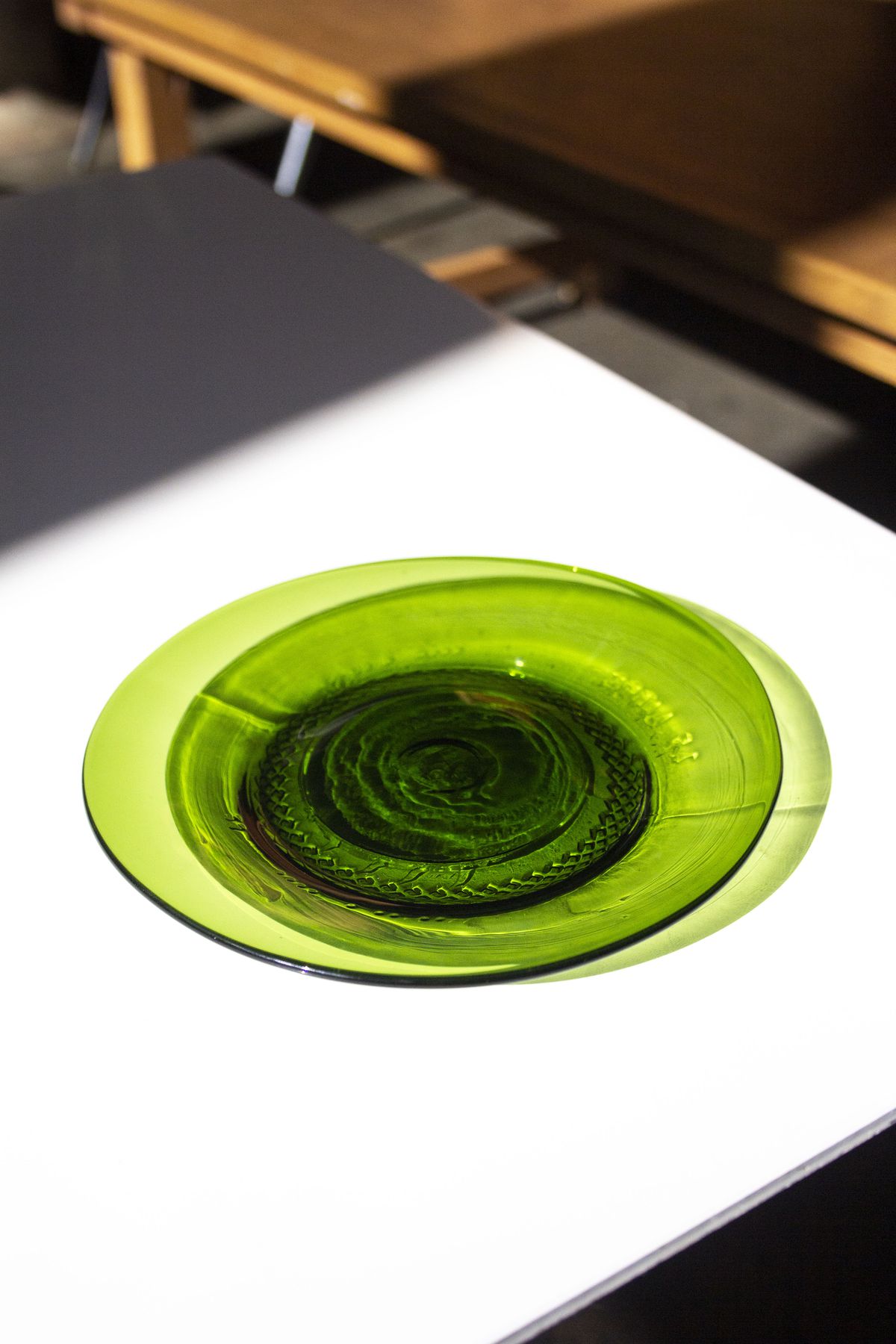 A round green glass sharing plate on a white table.