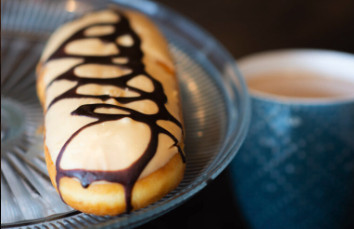 A chocolate-drizzled eclair and coffee.