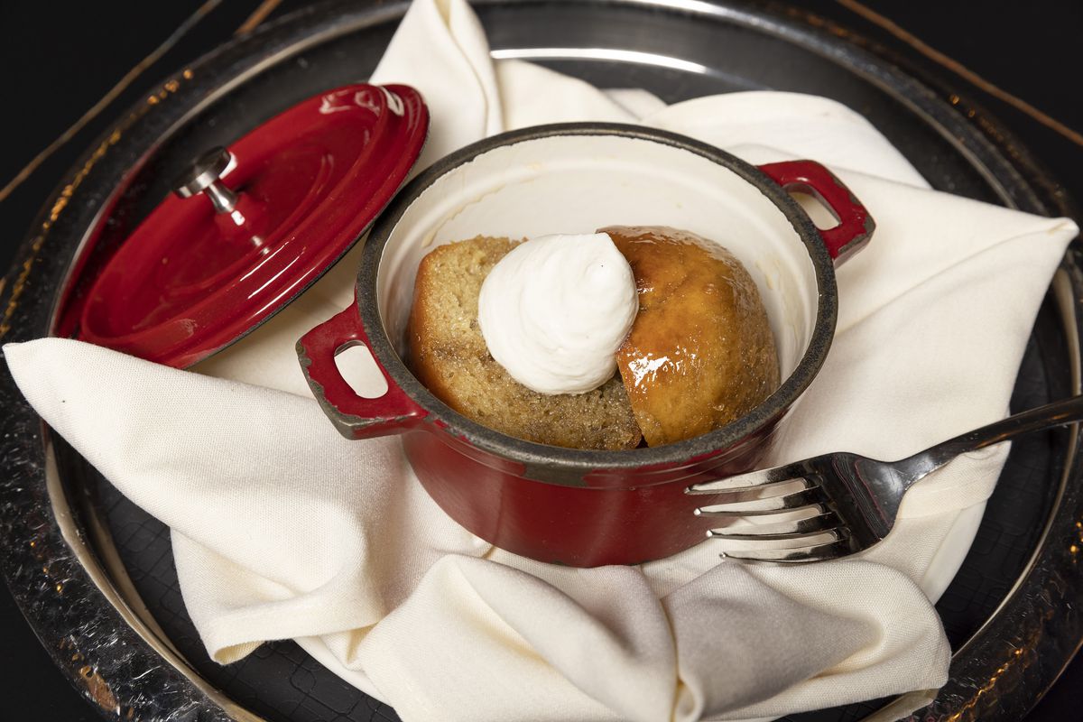 A small cast-iron pot holds a small cake topped with whipped cream.