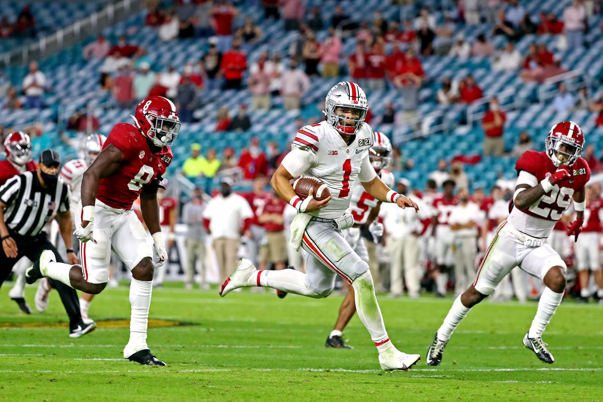 Ohio State Buckeyes quarterback Justin Fields (1) runs the ball against Alabama Crimson Tide linebacker Christian Harris (8) and defensive back DeMarcco Hellams (29) during the third quarter in the 2021 College Football Playoff National Championship Game.