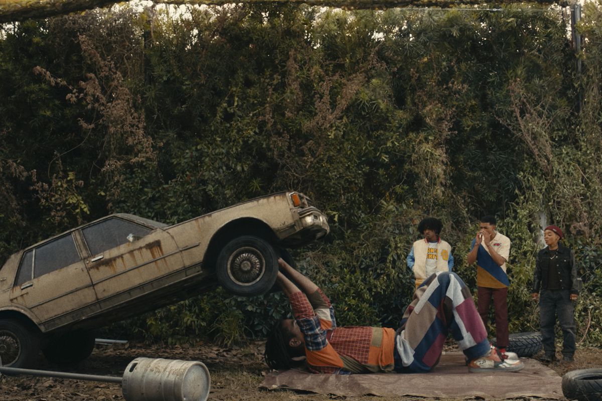 Cootie (Jharrel Jerome) bench pressing a car to impress his friends in a still from I’m a Virgo