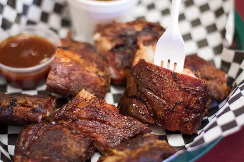 A close up of a plastic fork stabbing into a basket of rib tips