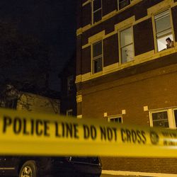 A women watches from a second-floor apartment as police investigate a person shot Sunday night in the 1800 block of West Cullerton. Tyler LaRiviere/Sun-Times