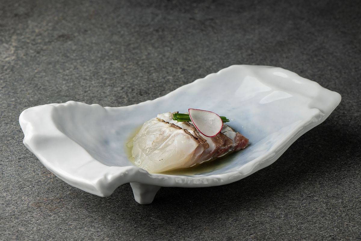 Raw fish, sliced thin, in a shell-like bowl.