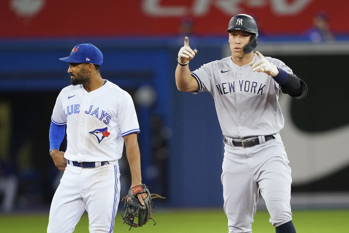 Aaron Judge of the New York Yankees celebrates his hit as Marcus Semien #10 of the Toronto Blue Jays looks on in the first inning at the Rogers Centre on September 28, 2021 in Toronto, Ontario, Canada.