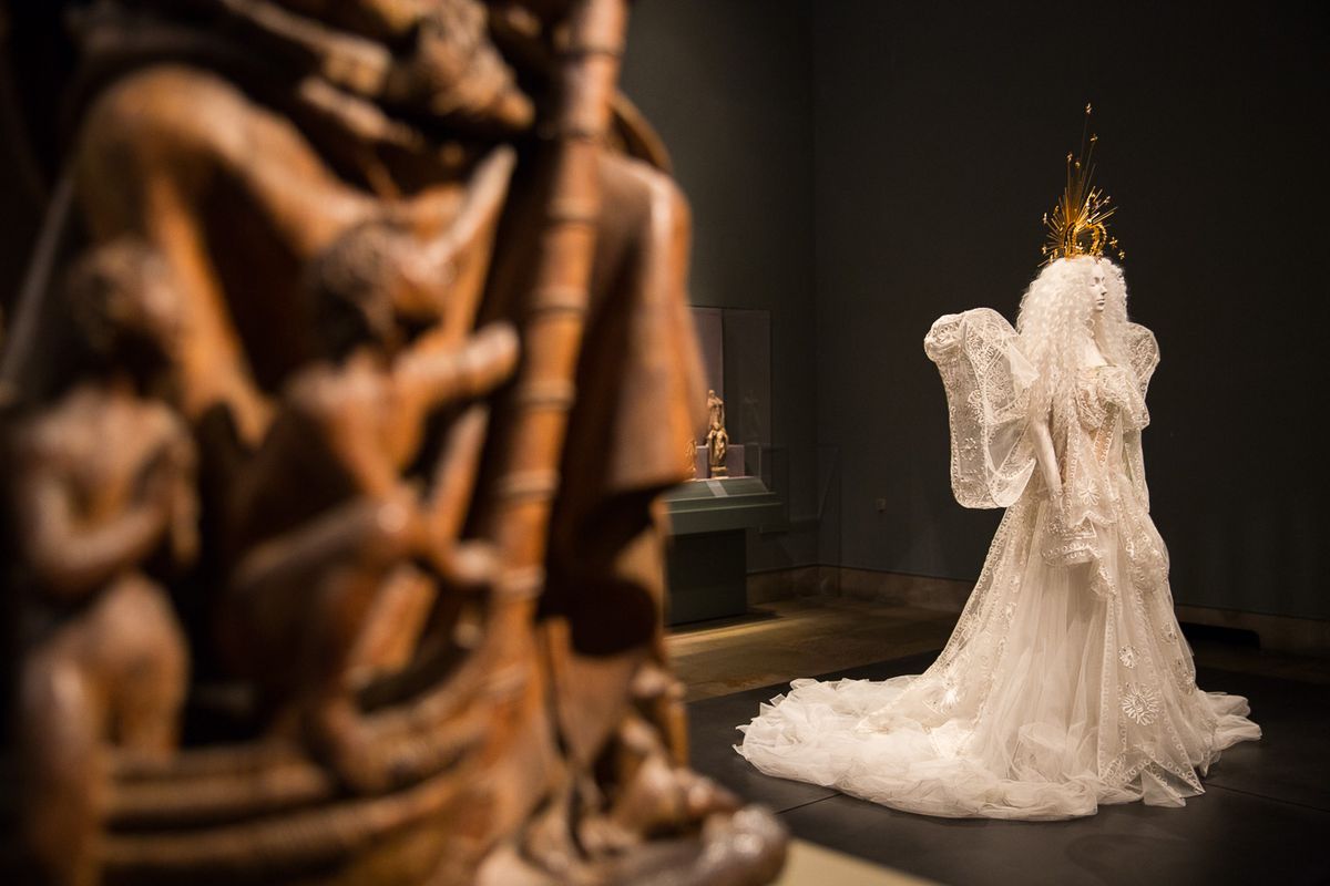 A model wears a frothy white wedding dress with angel wings.