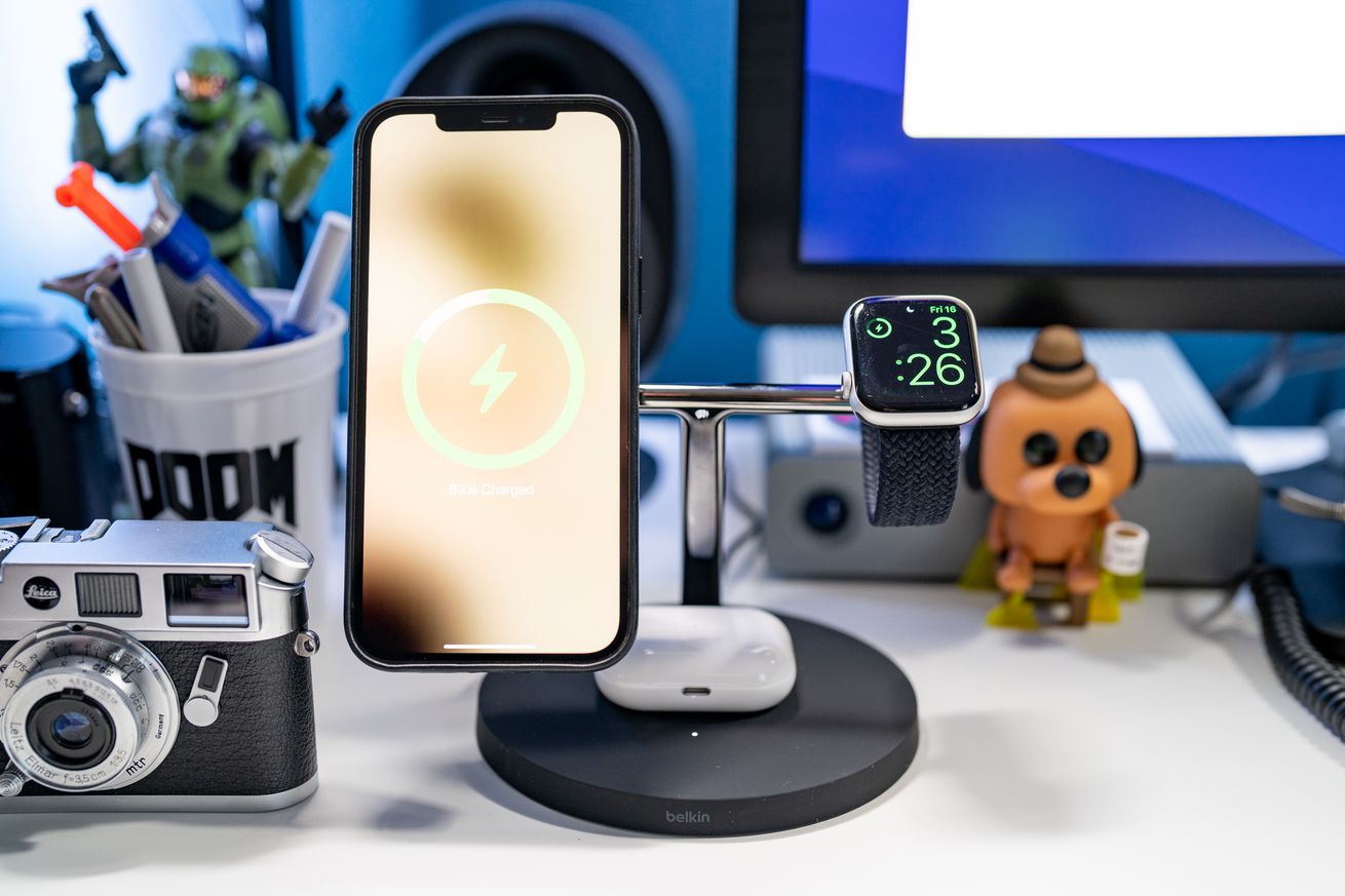 Belkin’s BoostCharge Pro 3-in-1 Wireless Charger charging a phone, an Apple smartwatch, and a pair of AirPods on a desk.
