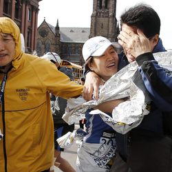An unidentified Boston Marathon runner, center, is reunited with loved ones near Copley Square following an explosion in Boston Monday, April 15, 2013. 