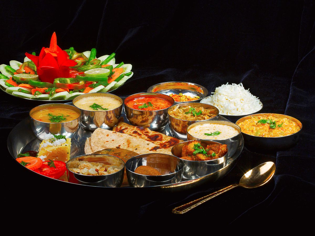A silver tray holds pieces of naan and various colored sanaa dipping sauces.