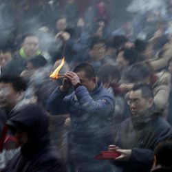 In this Thursday, Feb. 19, 2015, photo, a man holds burning incense as he offers prayers on the first day of the Chinese Lunar New Year at Yonghegong Lama Temple in Beijing, China. Chinese people are celebrating the arrival of the Lunar New Year, the Year of the Sheep. 