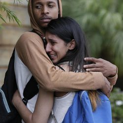 A weeping woman is comforted after being escorted off campus as Police swarm Santa Monica City College where a gunman shot numerous people Friday, June 7, 2013. A gunman with an assault-style rifle killed at least six people in Santa Monica on Friday before police shot him to death in a gunfight in the Santa Monica College library, authorities said. 