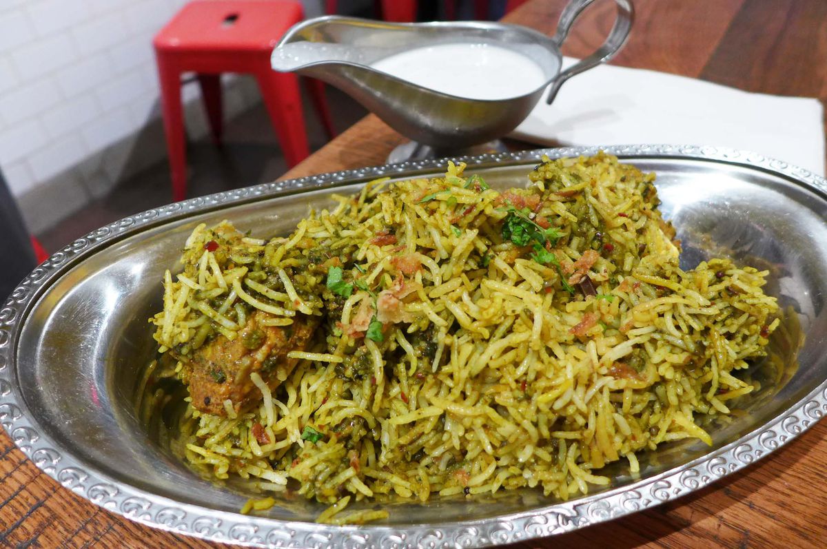 Greenish brownish rice with herbs visible in a heap of biryani.