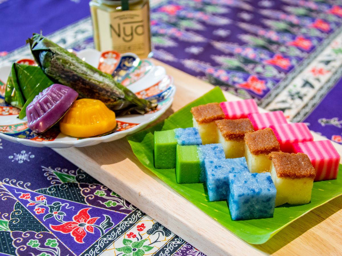 Brightly colored snacks in various shapes and sizes, some served on a decorative plate, others on a leaf, all set on a decorative tablecloth