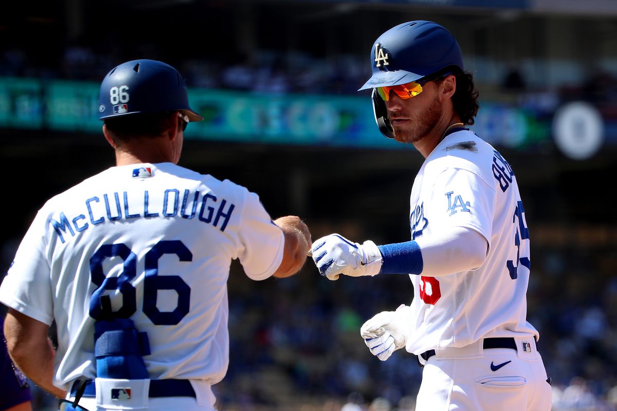 Cody Bellinger of the Los Angeles Dodgers celebrates his single with first base coach Clayton McCullough during the fifth inning against the Colorado Rockies at Dodger Stadium on August 29, 2021 in Los Angeles, California.