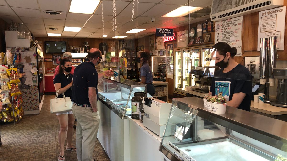 Washtenaw Dairy Ice Cream store has a protective shield blocking customers from employees who are wearing black cloth face masks.