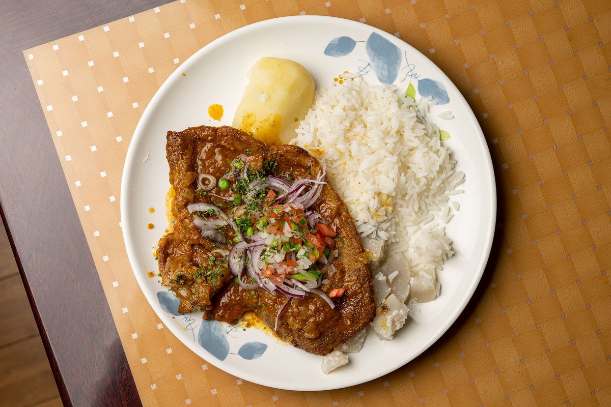 An overhead shot of a slow cooked tongue with rice and potatoes and red onions.