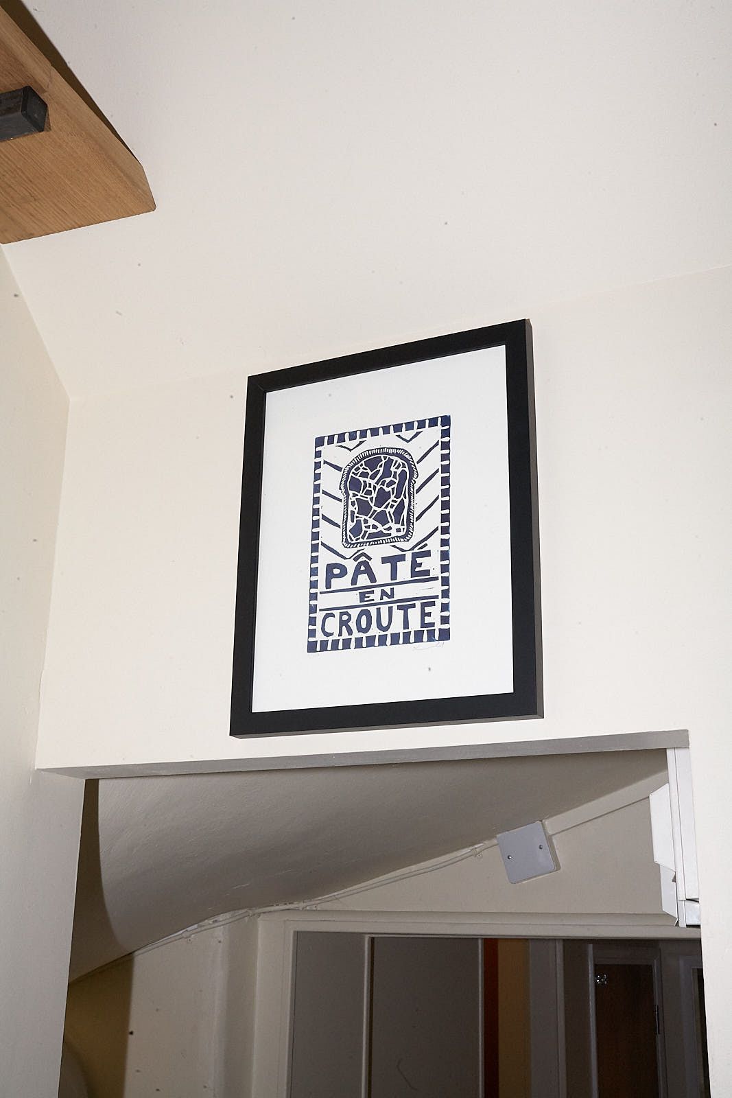 A white print with the words paté en croute in blue type, with a cut-through of the charcuterie in the centre.