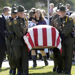 The casket carrying the body of U.S. Border Patrol agent Nicholas J. Ivie arrives for interment in Spanish Fork, Thursday, Oct. 11, 2012. At back is Christy Ivie, wife of Nicholas J. Ivie, carrying her 22-month-old daughter, Presley.
