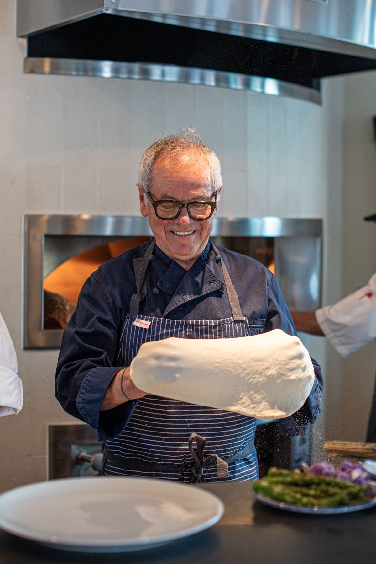 Wolfgang Puck stretches pizza dough.
