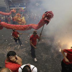 Firecrackers explode as dragon and lion dancers perform in front of a supermarket in Manila's Chinatown district to celebrate the Chinese New Year Thursday, Feb. 19, 2015, in the Philippines. This year marks the "Year of the Sheep" in the Chinese Lunar calendar. 