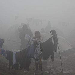 A migrant woman hangs clothes to dry at the northern Greek border station of Idomeni, Tuesday, March 8, 2016. Greek police officials said Macedonian authorities have imposed further restrictions on refugees trying to cross the border, saying only those from cities they consider to be at war can enter. 