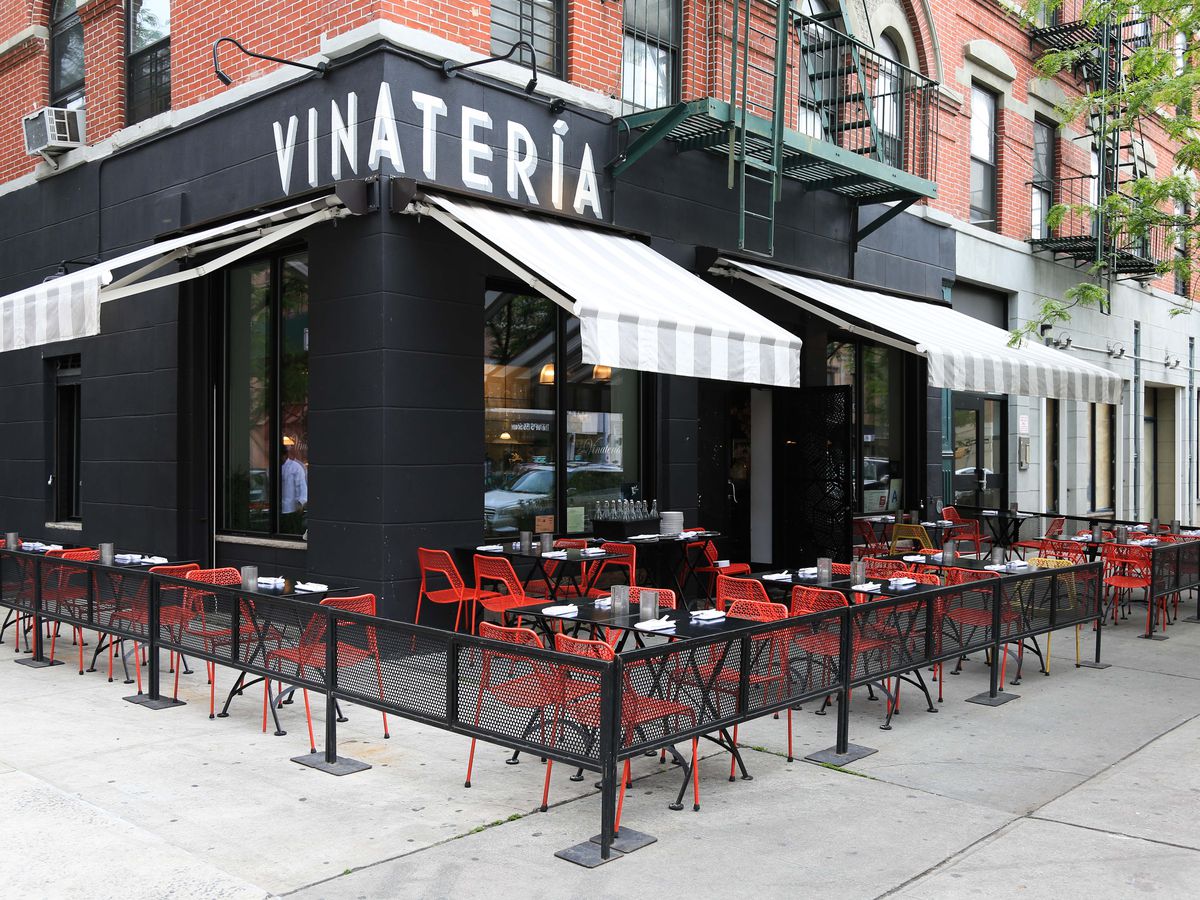 The exterior of Vinatería with red table and chairs on the sidewalk