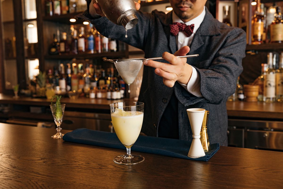 A bartender mixes a cocktail at a bar.