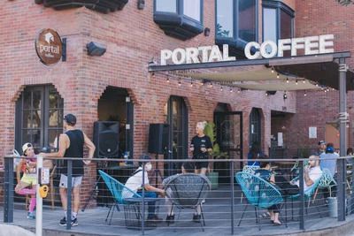 Portal’s patio, with a brick facade and people sitting outside drinking, dining and socializing.