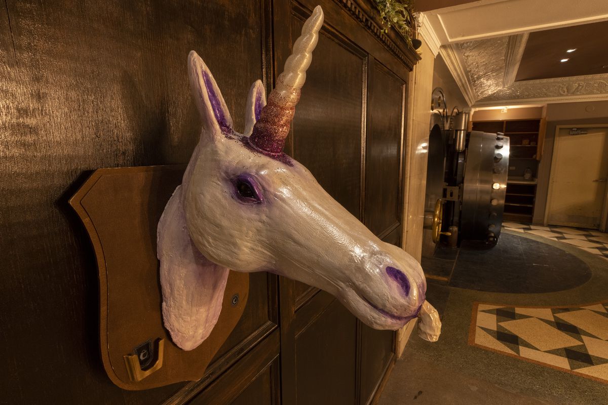 A mounted unicorn head that contains a drink dispenser.