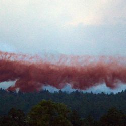 A DC-10 Air Tanker drops fire retardant near home in the evening as the Black Forest Fire continues to burn out of control for a second straight day near Colorado Springs on Wednesday, June 12, 2013. The fire has consumed 11,500 acres. It has destroyed 92 homes and damaged others. The erratic fire has forced the evacuation of thousands of people.  (AP Photo/BryanOller)