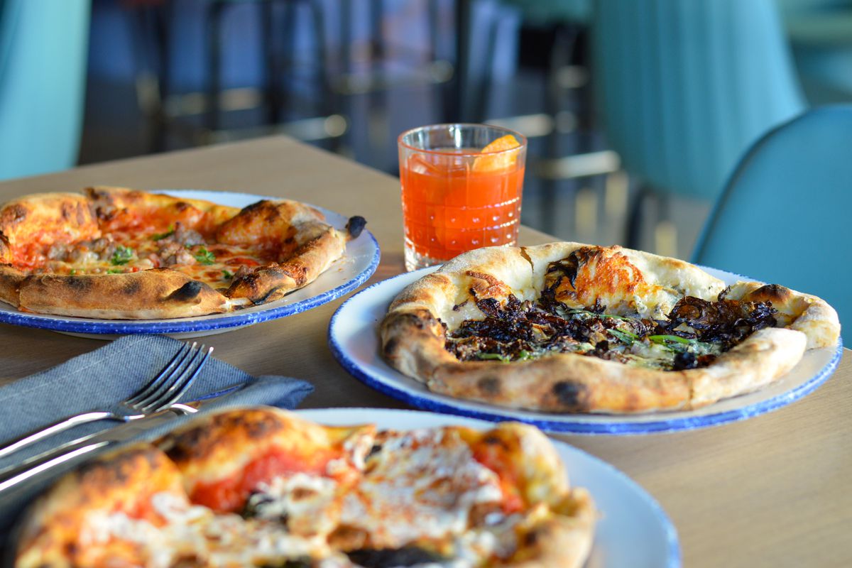 A table laid with three Neapolitan pizzas.