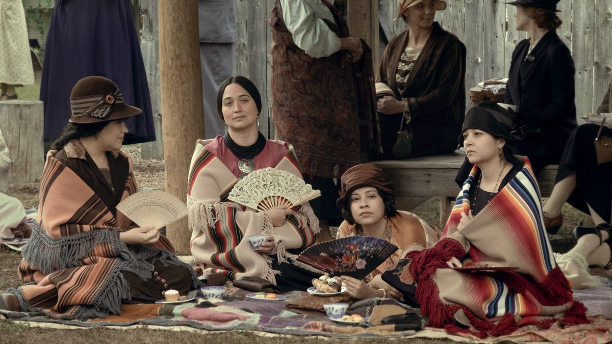 Lily Gladstone, holding a fan, sits at the center of a group of well-dressed Osage women in Killers of the Flower Moon