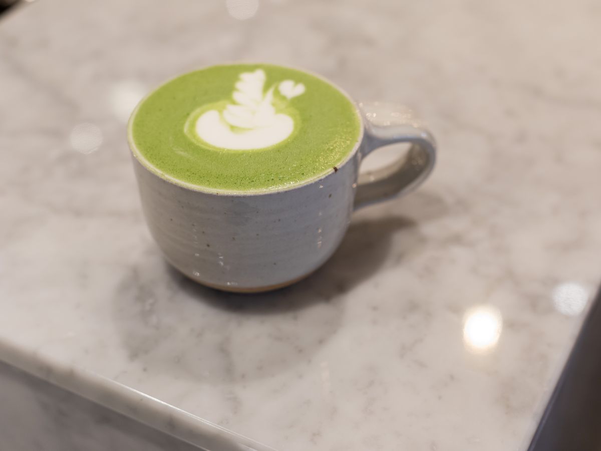 A bright green matcha latte on a marble counter