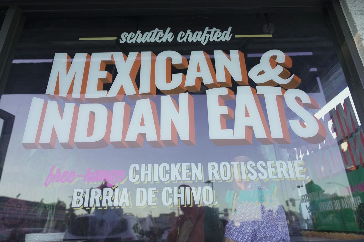 The entry sign that says “Scratch crafted Mexican and Indian eats” and “Free range chicken rotisserie, birria chivo” at Saucy Chick Goat Mafia restaurant in Pasadena.