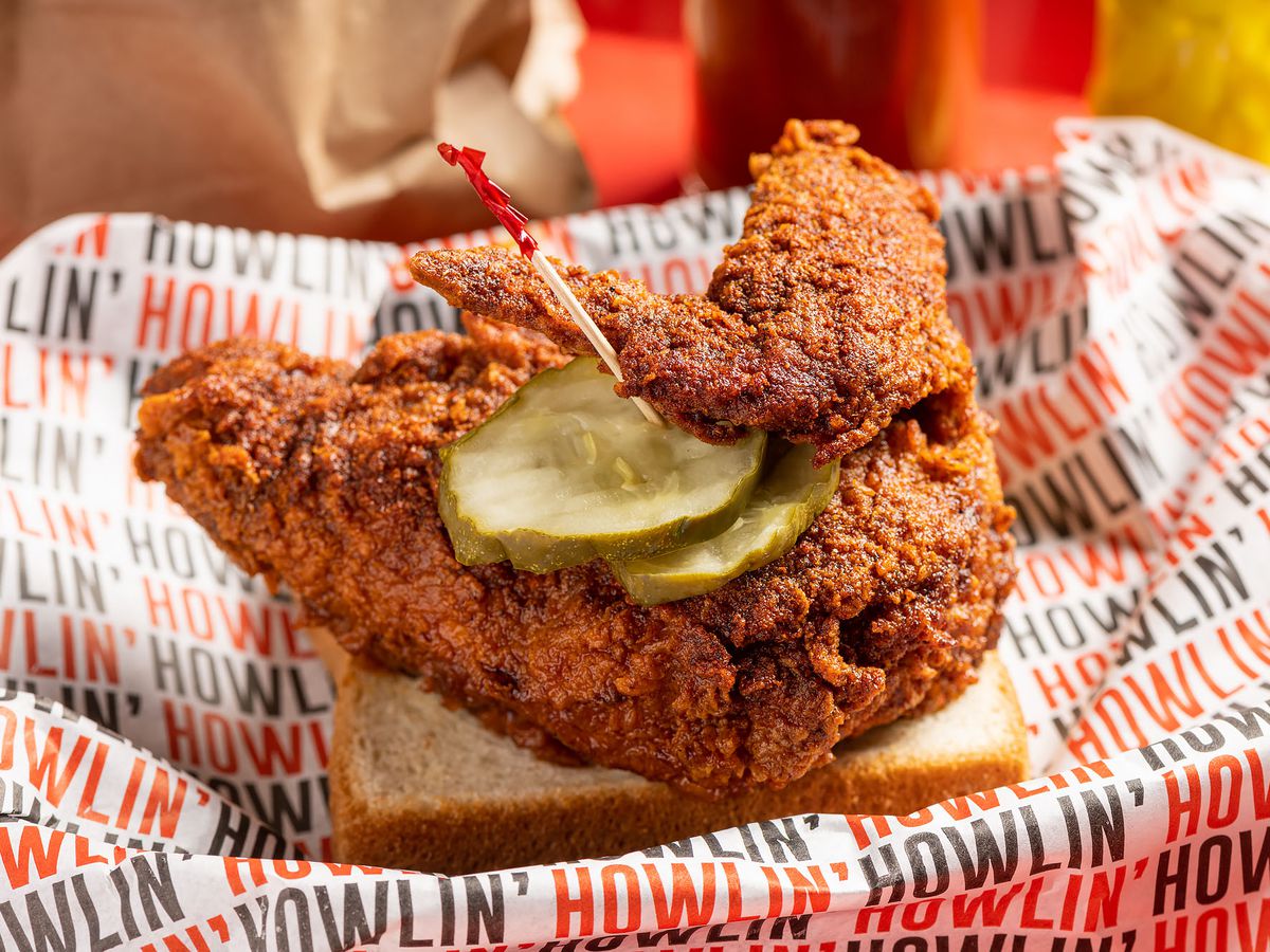 A close-up shot of hot chicken on with pickles on a piece of white bread at Howlin’ Ray’s.