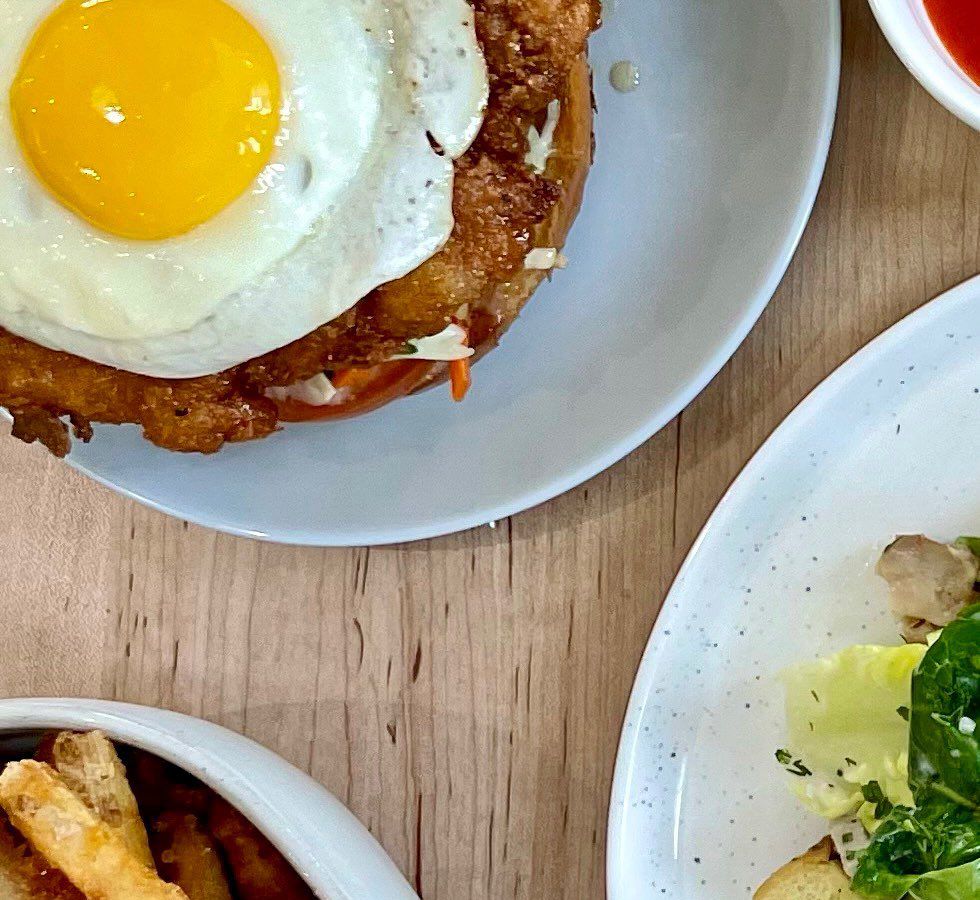 A sunny side up egg with chicken, hot honey, on a brioche bun