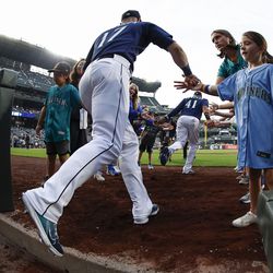 SEATTLE, WASHINGTON - SEPTEMBER 27: Fans slap hands with Mitch Haniger #17 and Carlos Santana #41 of the Seattle Mariners as they take the field before the game against the Texas Rangers at T-Mobile Park on September 27, 2022 in Seattle, Washington