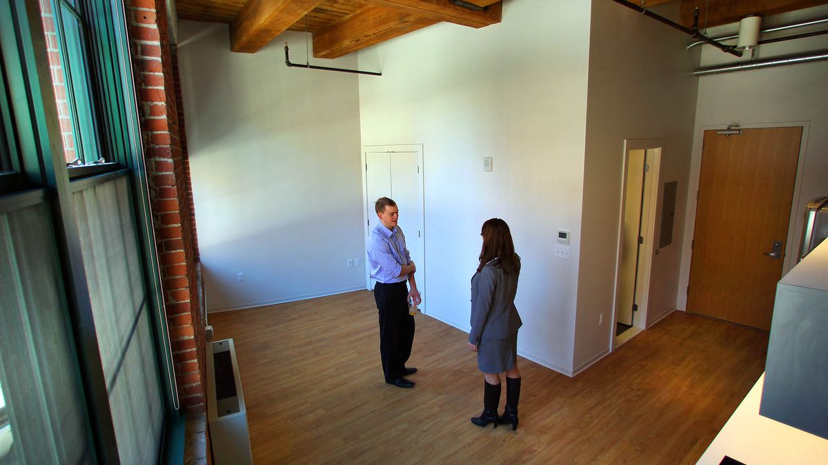 A very small and empty apartment with two people standing in the middle of it.