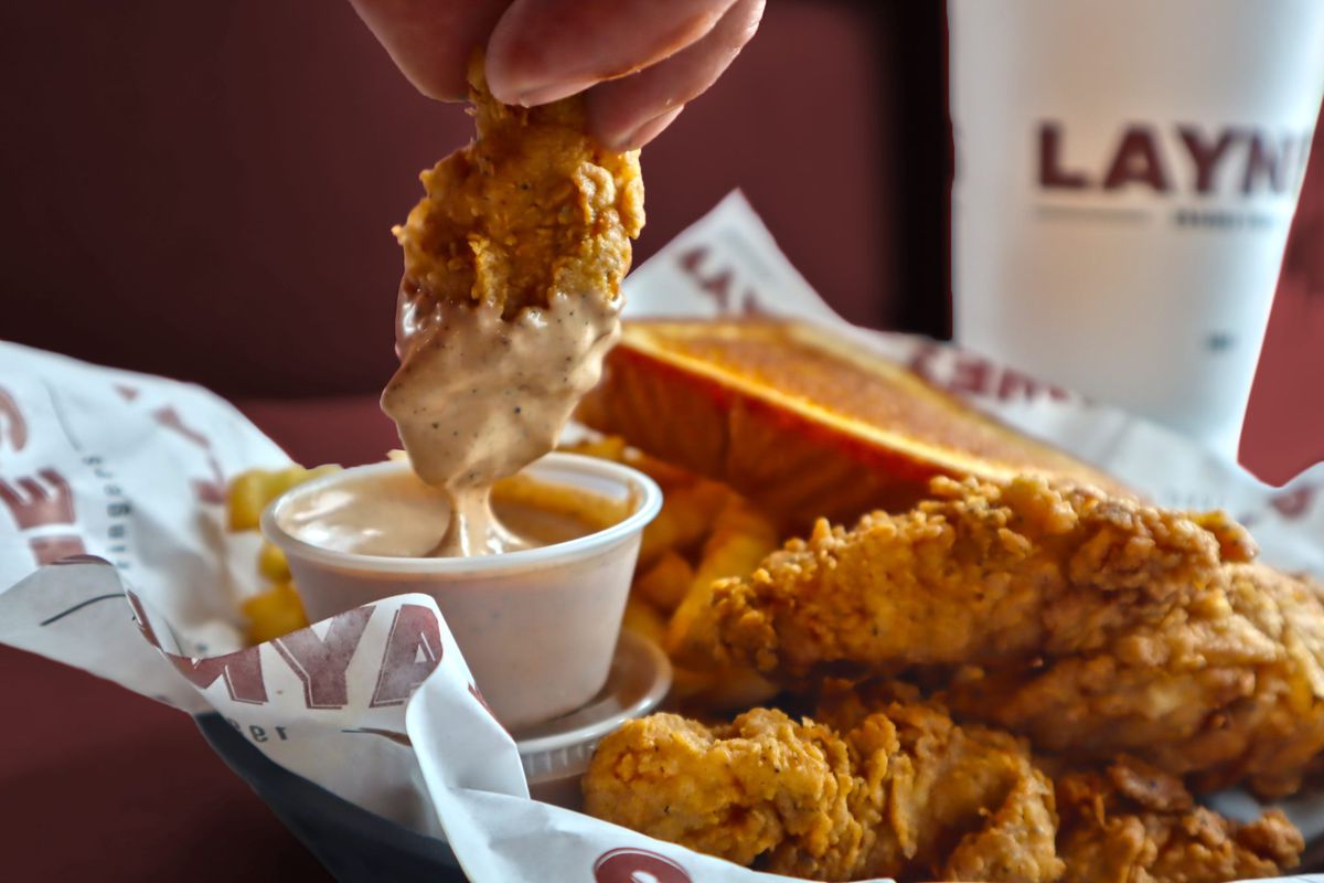 a person dipping a chicken finger into a cup of sauce