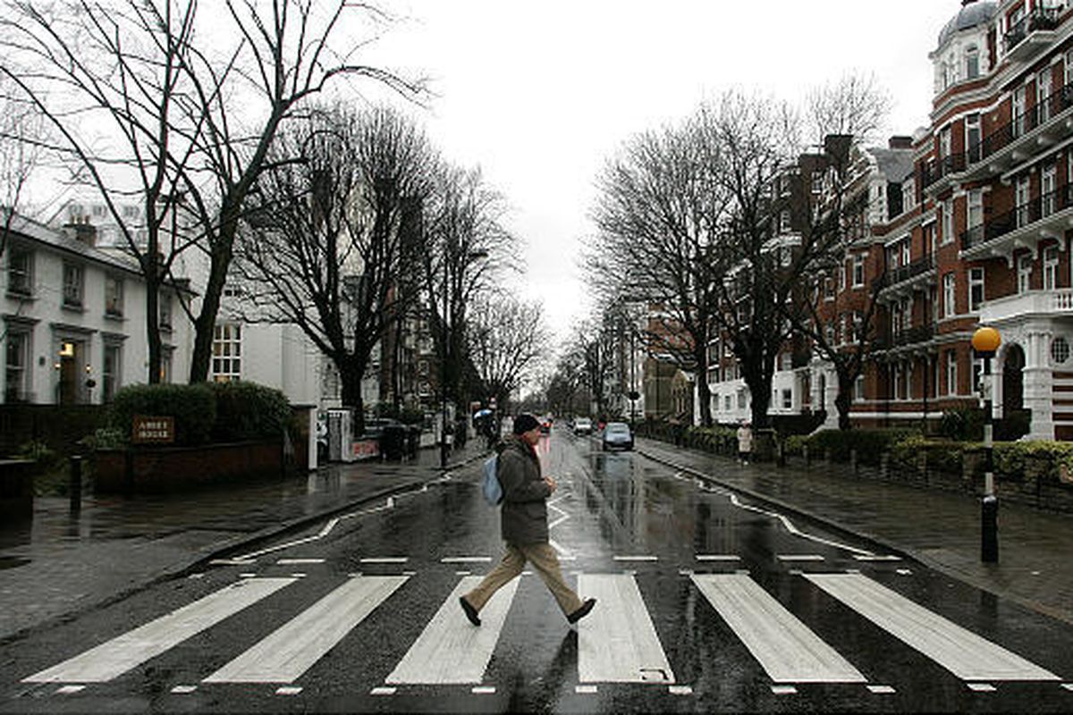 A man walks on the zebra crossing made famous from the album cover of The Beatles’ ‘Abbey Road’ in front of Abbey Road Studios, seen at left, in London, Feb. 16, 2010.