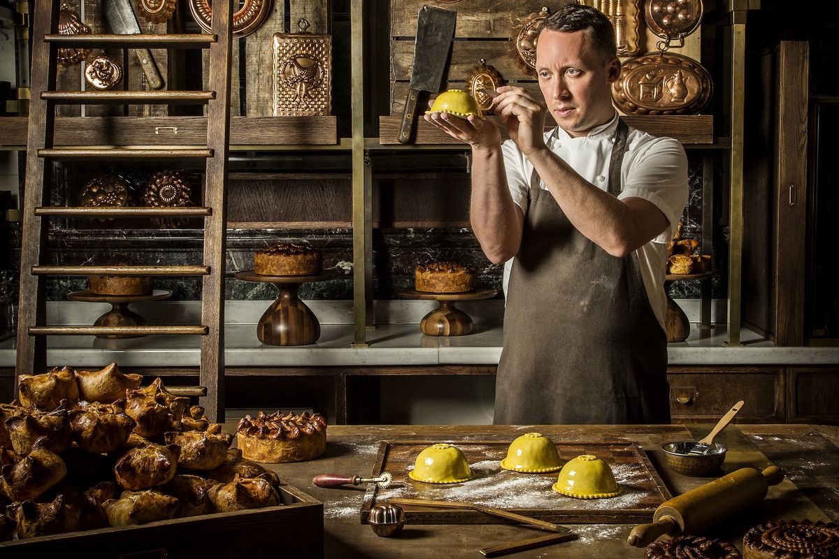 Chef Calum Franklin stands surrounded by pastry paraphernalia, scoring pastry before baking