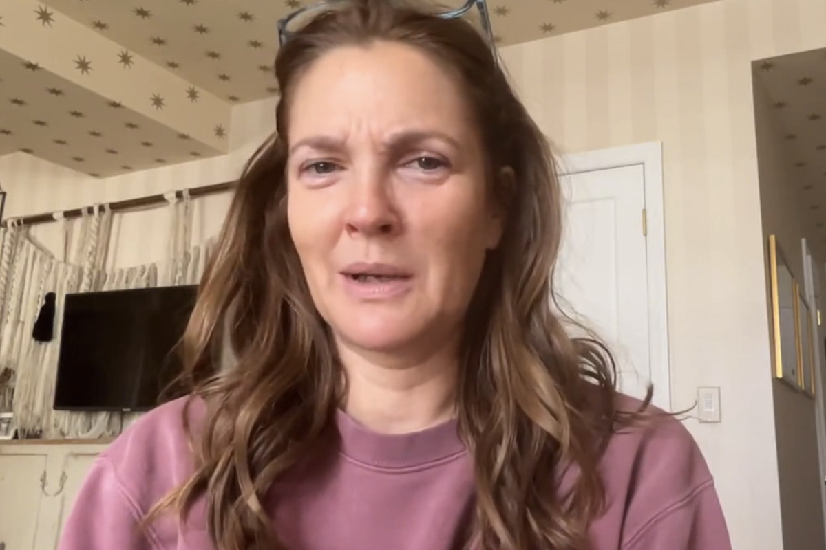 Drew Barrymore without makeup, in a casual sweatshirt, filming her apology video from home. 