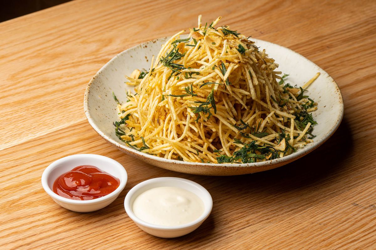 A pile of french fries cut very thin on a light stone bowl.