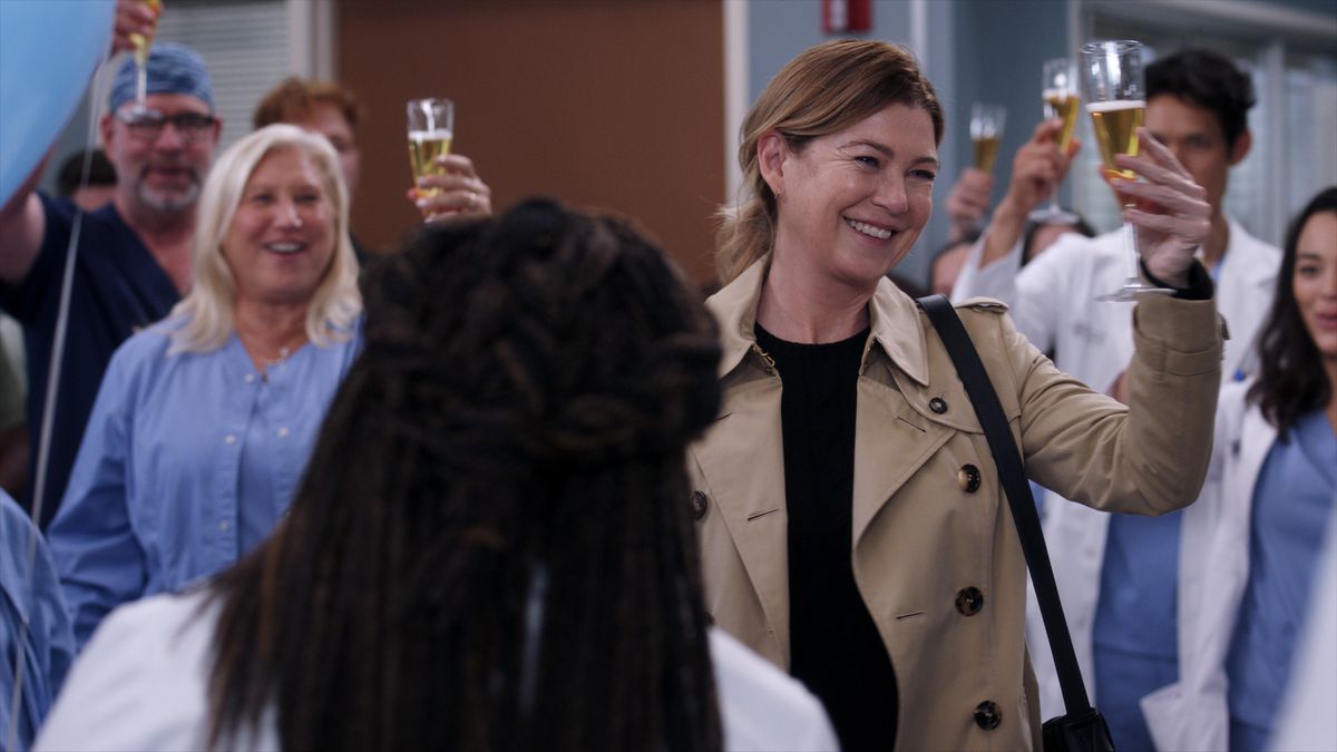 Meredith Grey (Ellen Pompeo) toasting champagne as she leaves the hospital, with people behind her toasting her as well